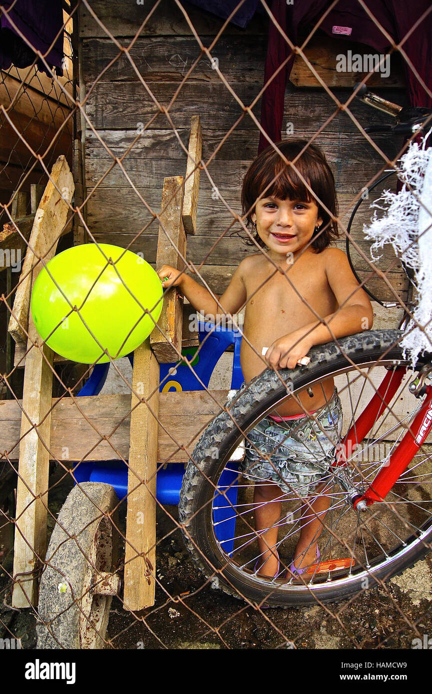 Honduras:  Baby girl smiling at the camera through the fence from her squatter. Stock Photo