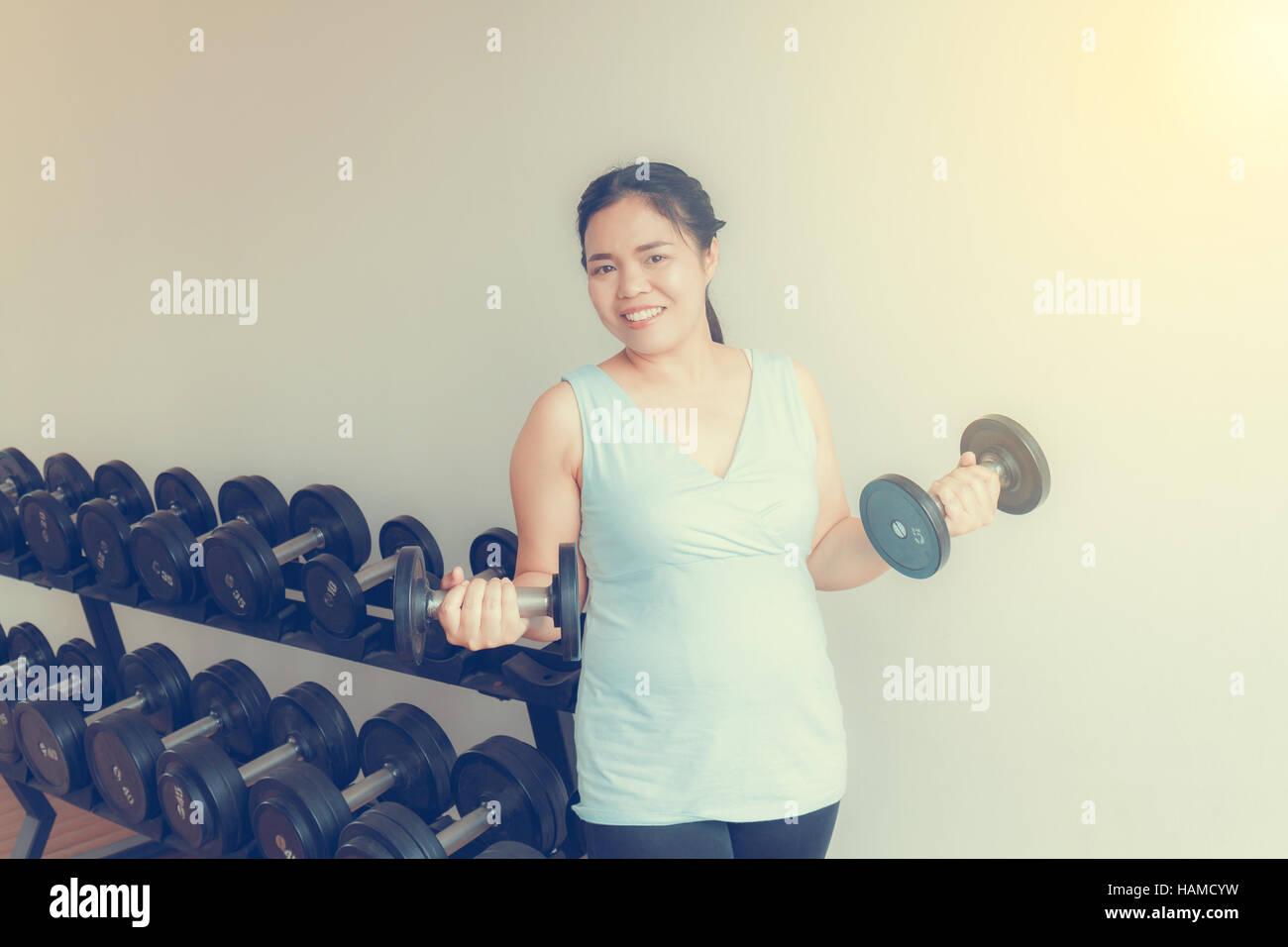Asia fat woman training dumbbell in the gym for strength, weight loss. Stock Photo