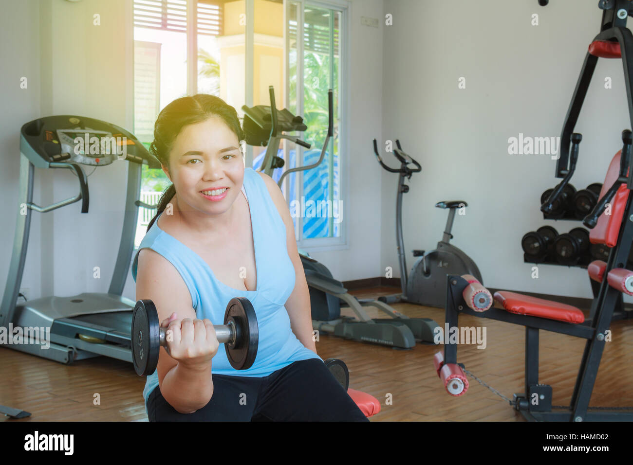 Asia fat woman training dumbbell in the gym for strength, weight loss. Stock Photo
