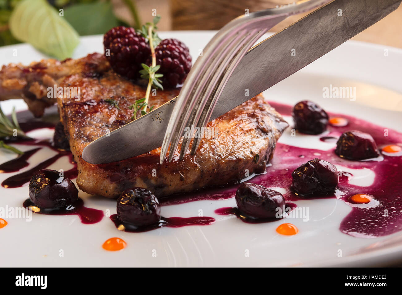 Concept: restaurant menus, healthy eating, homemade, gourmands, gluttony. Sliced pieces of pork steak on the bone with cherry-ginger sauce with ingred Stock Photo