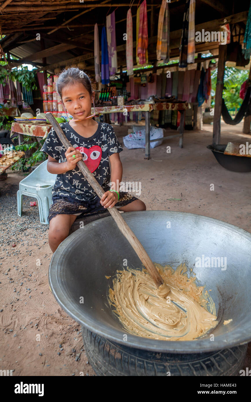 A ten-year old Khmer girl makes Palm Sugar Candy for selling to tourists on the road to Banteay Srei, Kingdom of Cambodia. Stock Photo