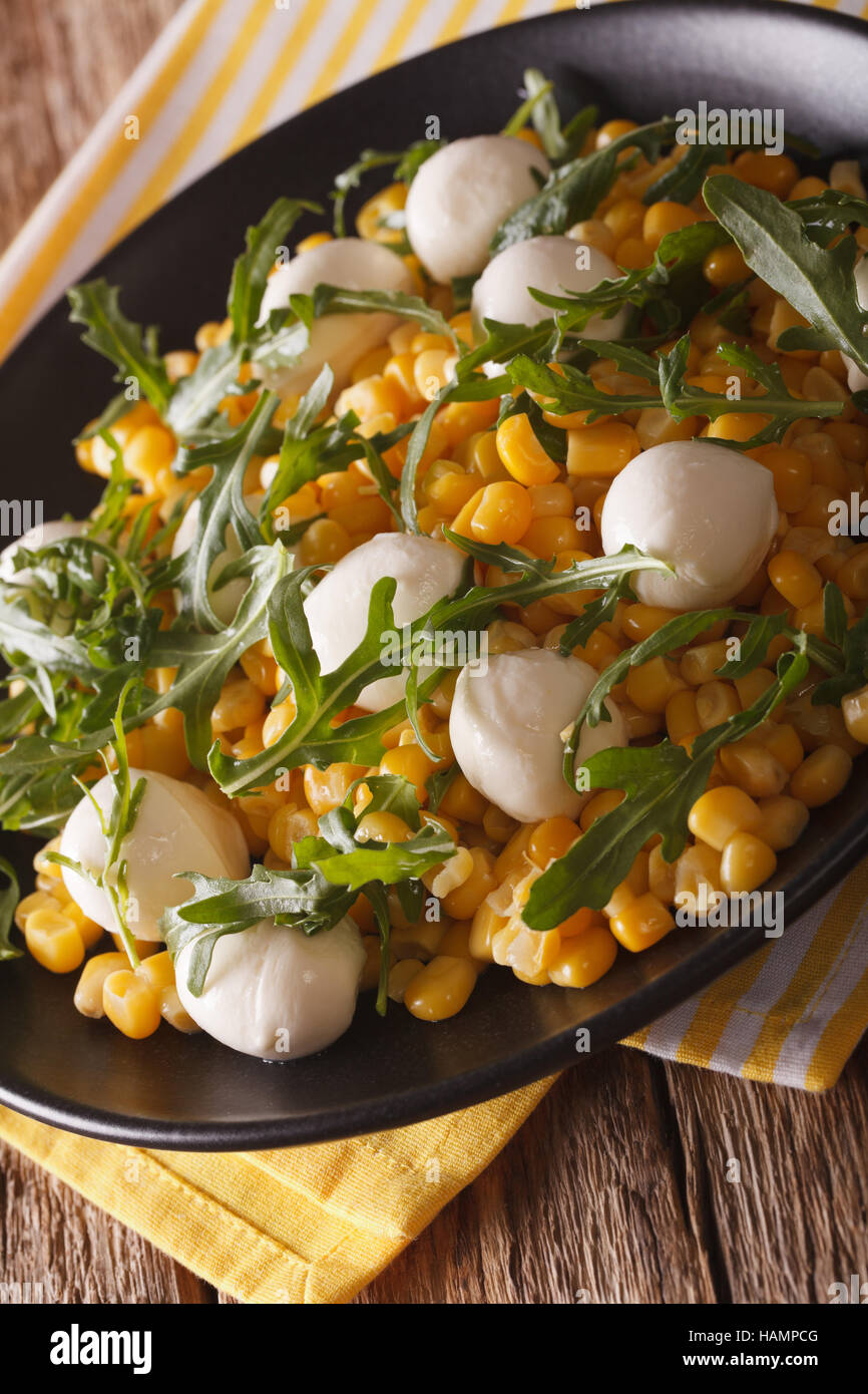 Low calorie salad of corn, baby mozzarella and arugula close-up on a plate. vertical Stock Photo