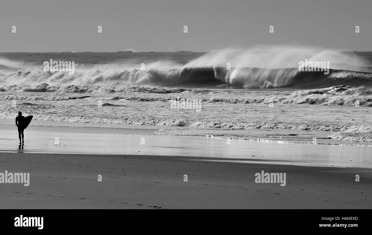 A surfer observes with his board in his hand from the shore the big waves Stock Photo