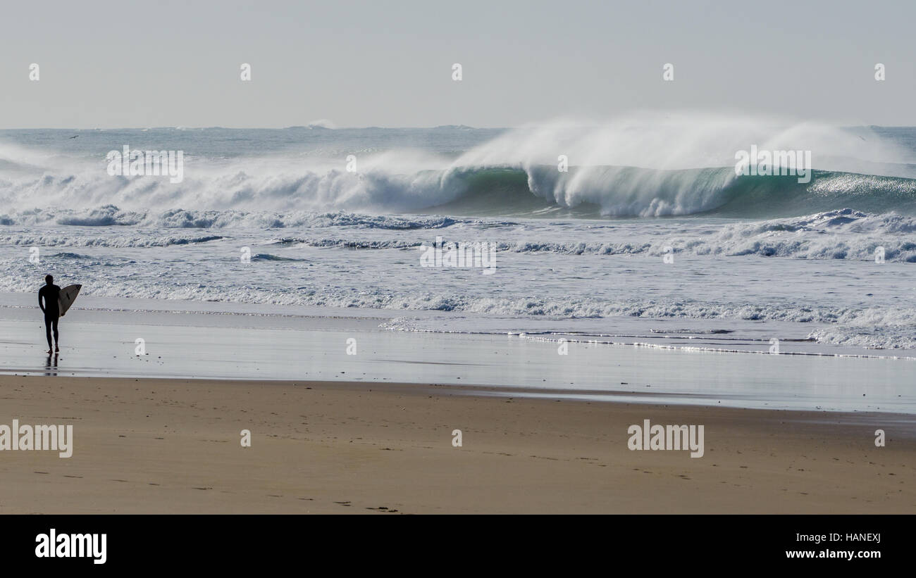 A surfer observes with his board in his hand from the shore the big waves Stock Photo