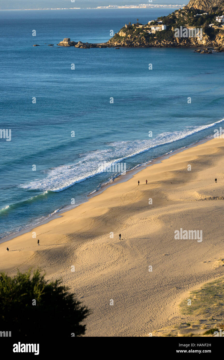 A photograph of a landscape of a beach and the Costa de la Luz where a group of people stroll relaxed by the shore Stock Photo
