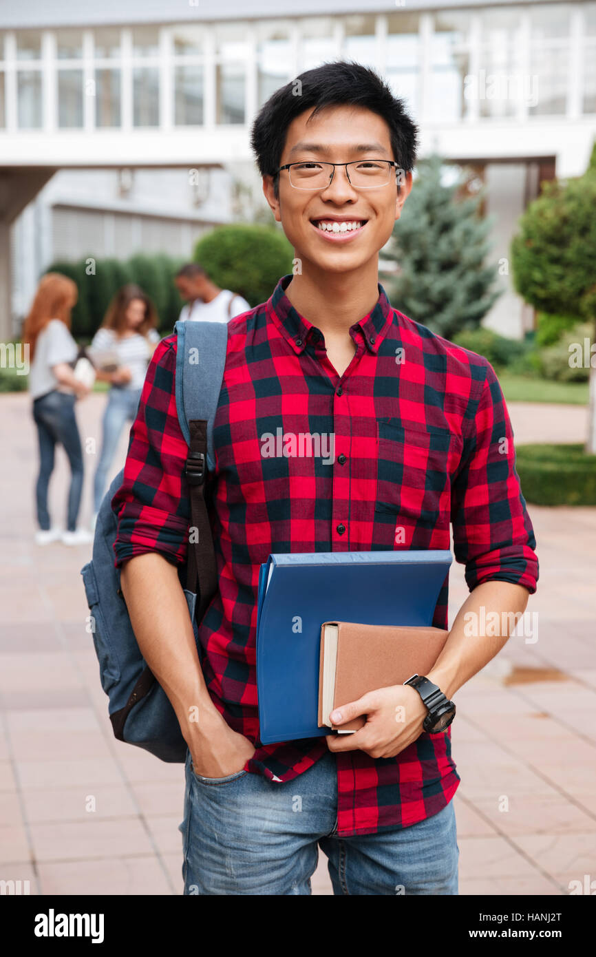 Happy asian young man student in glasses and plaid shirt with backpack ...
