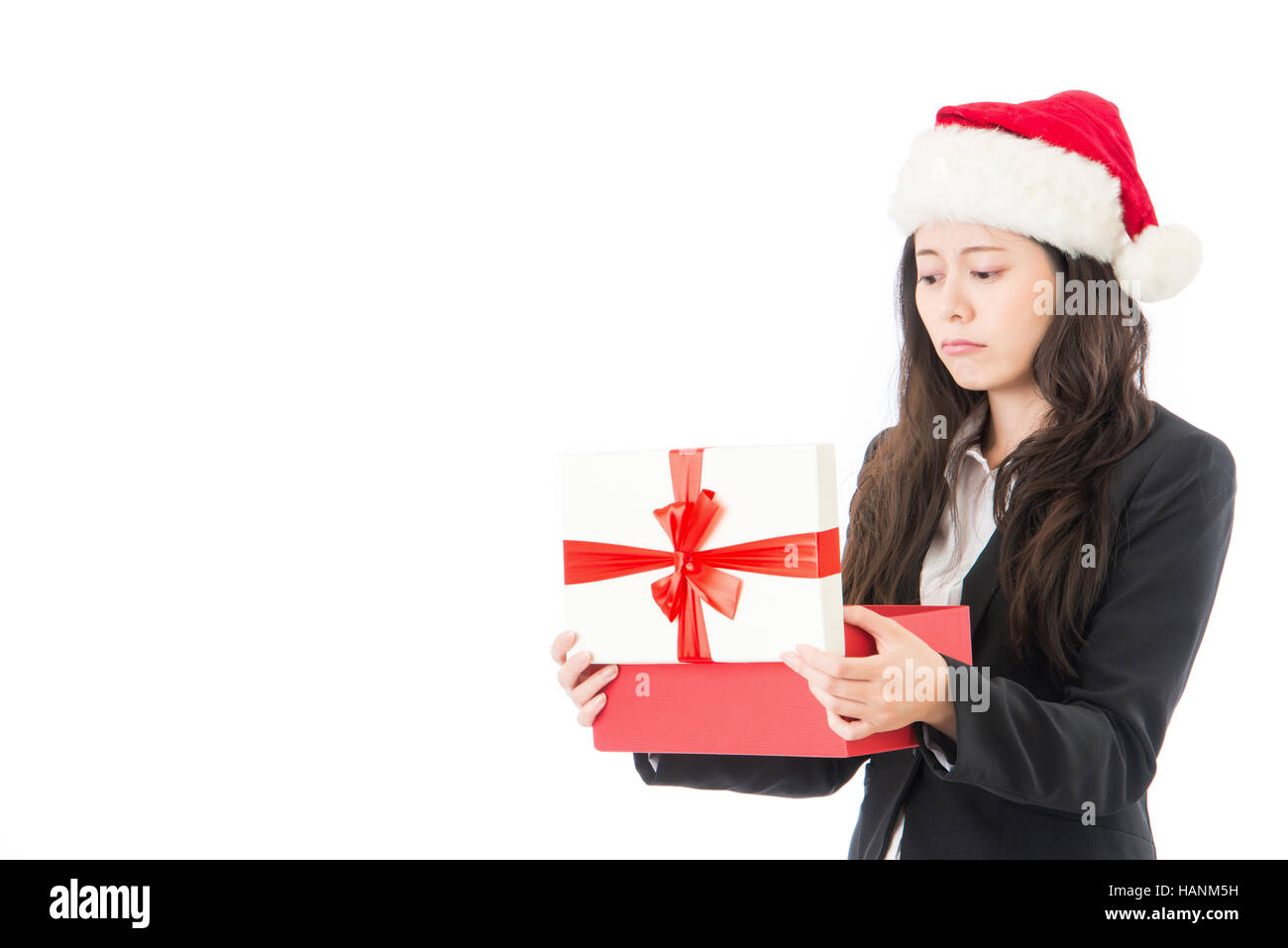 woman opening Christmas gift disappointed and unhappy, Young woman in Santa hat. Funny cute photo of Asian woman isolated on white background. Stock Photo