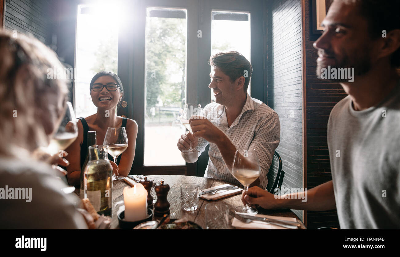 Young men and women having wine at restaurant. Group of friends drinking wine at a bar. Stock Photo