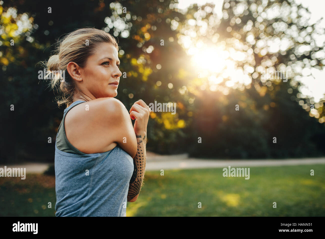 Portrait of fitness woman stretching arms in the park. Caucasian female working out in the morning. Stock Photo