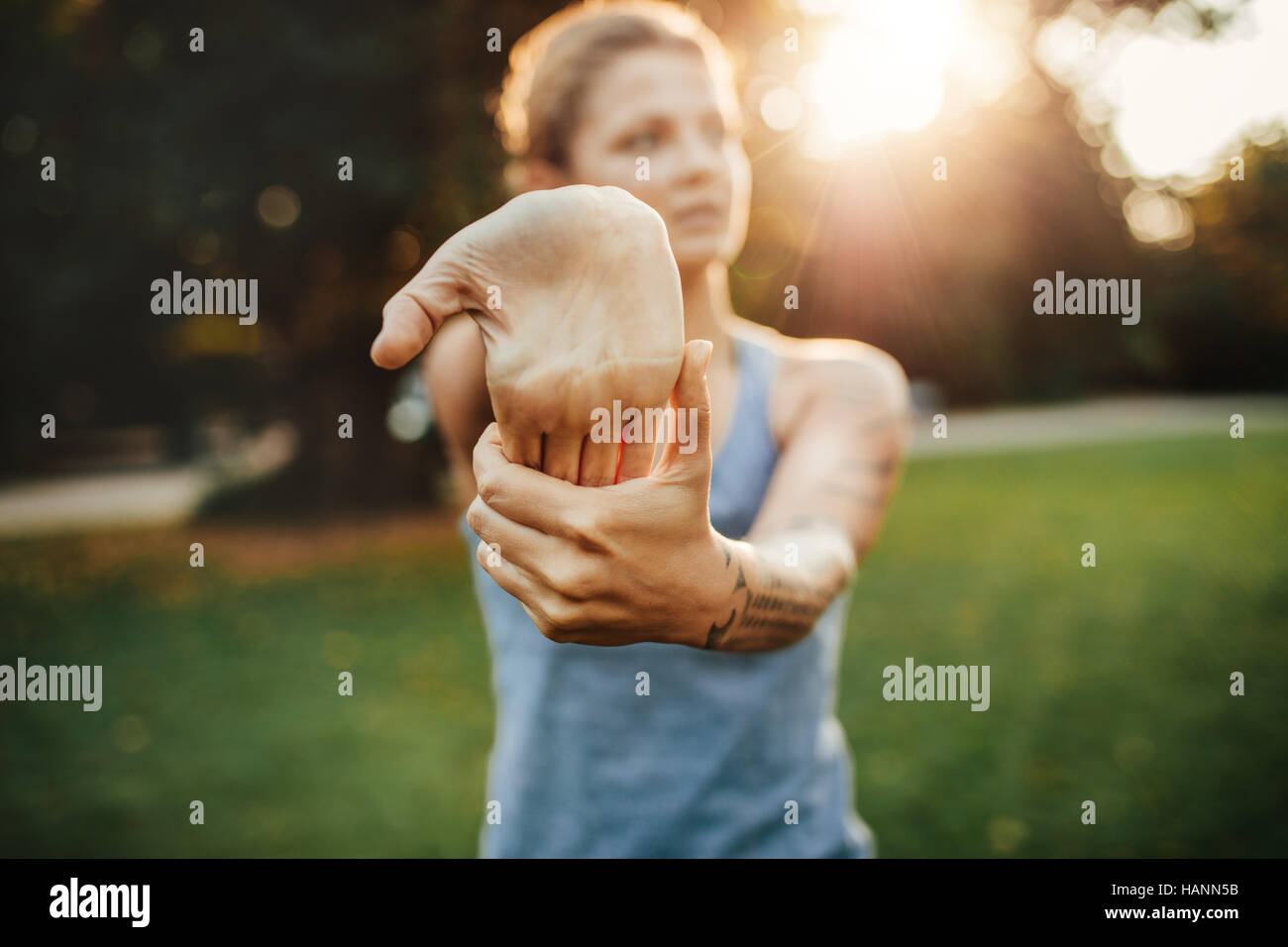 Young woman stretching hand muscles before workout. fitness female stretching at the park. Stock Photo