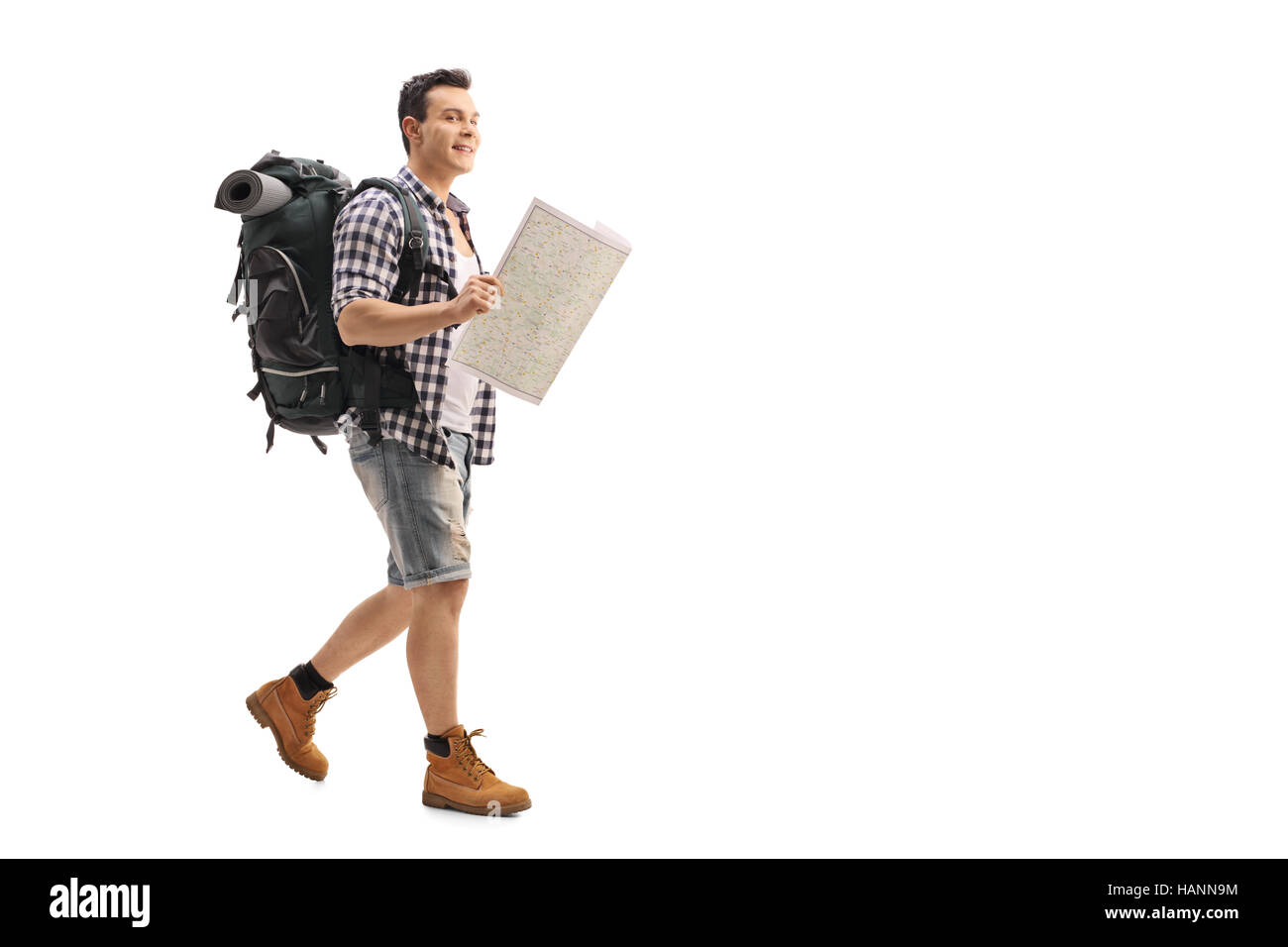 Full length portrait of a hiker walking and holding a generic map isolated on white background Stock Photo