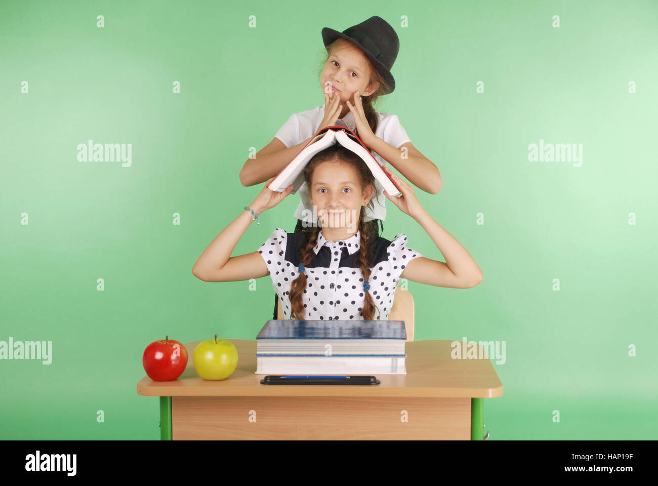 Two girl in a school uniform sitting at a desk and reading a book ...