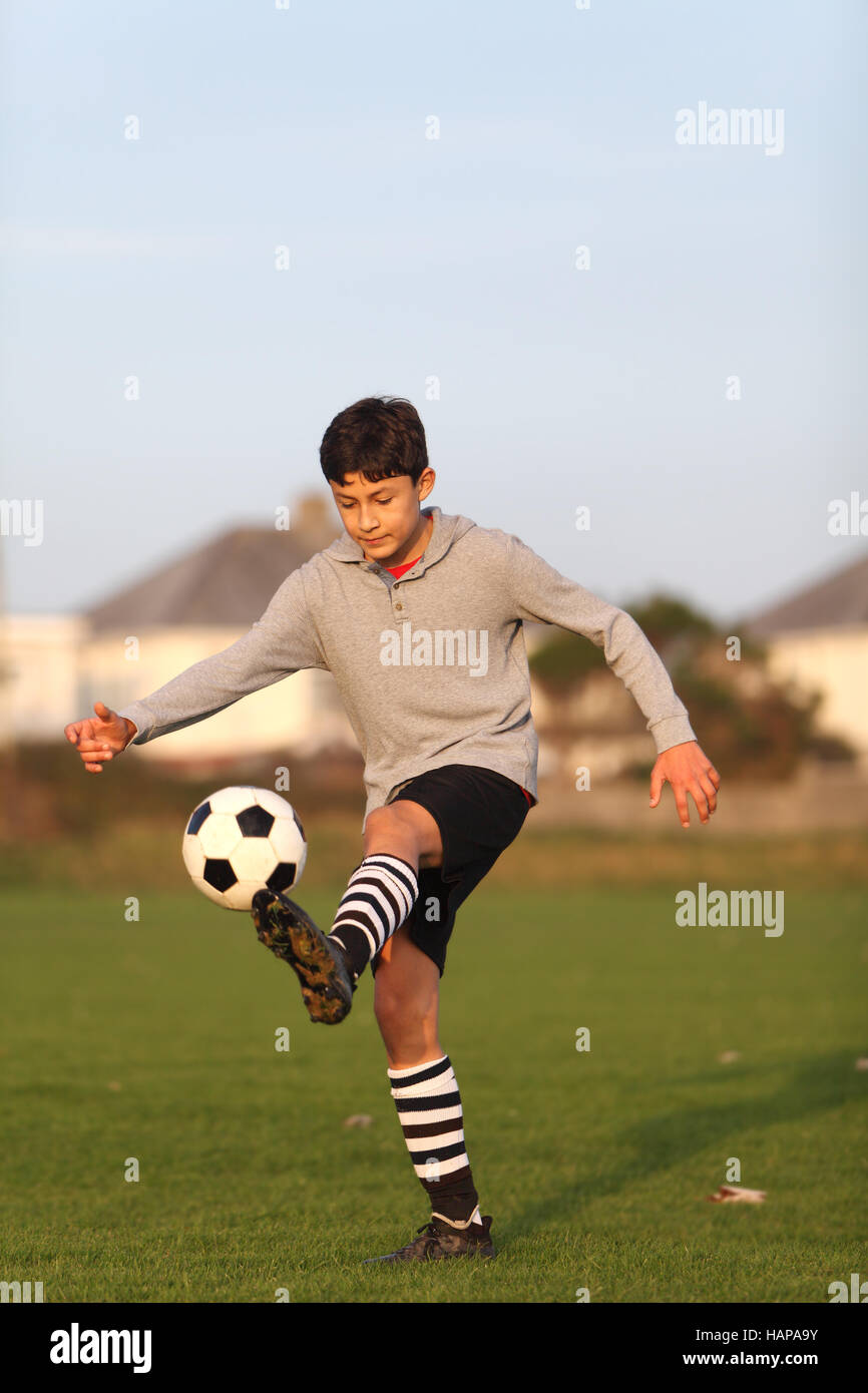 Boy with soccer ball outside in the golden hour near sunset Stock Photo