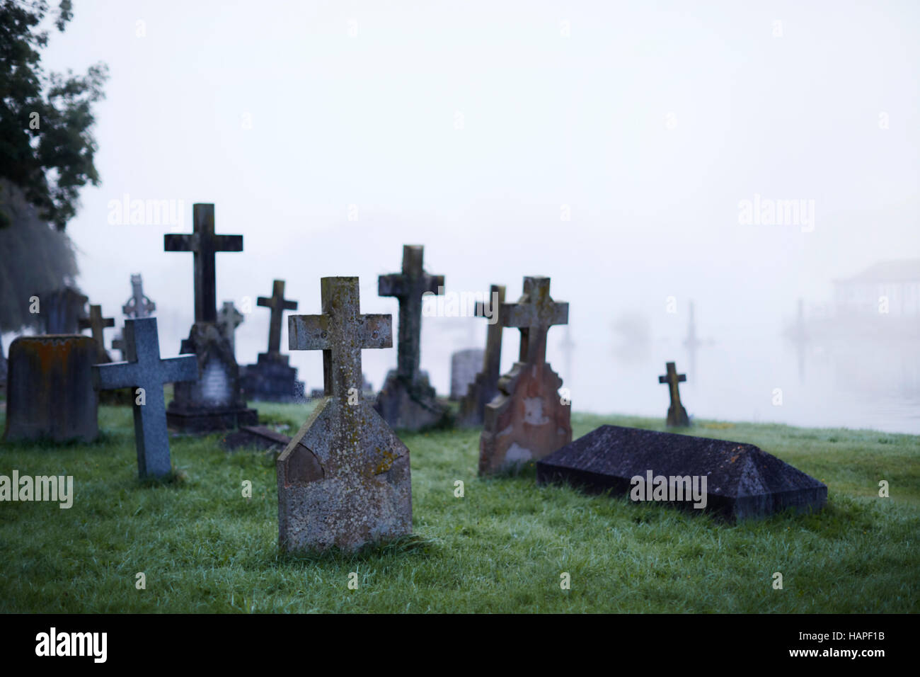 Crosses on gravestones in ethereal foggy cemetery Stock Photo