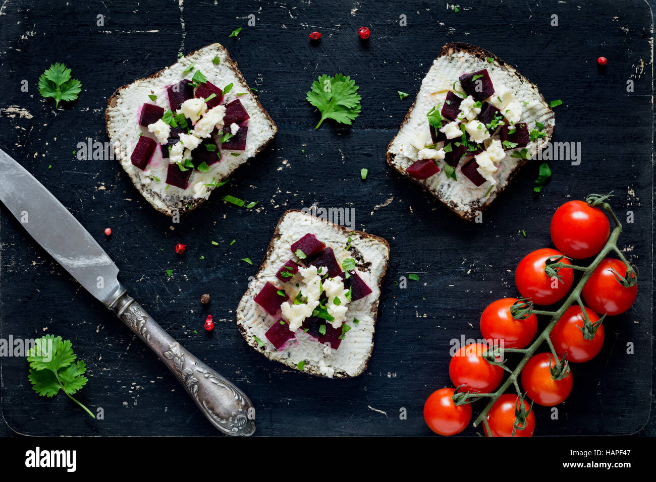 Goat cheese, roasted beet and feta cheese appetizer sandwiches on black cutting board, top view