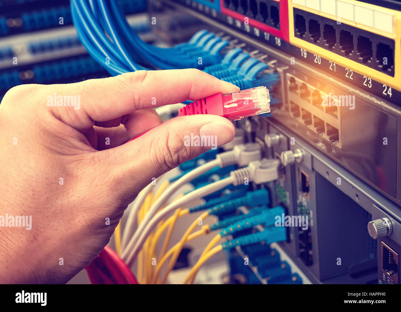 hand with network cables connected to servers in a datacenter Stock Photo