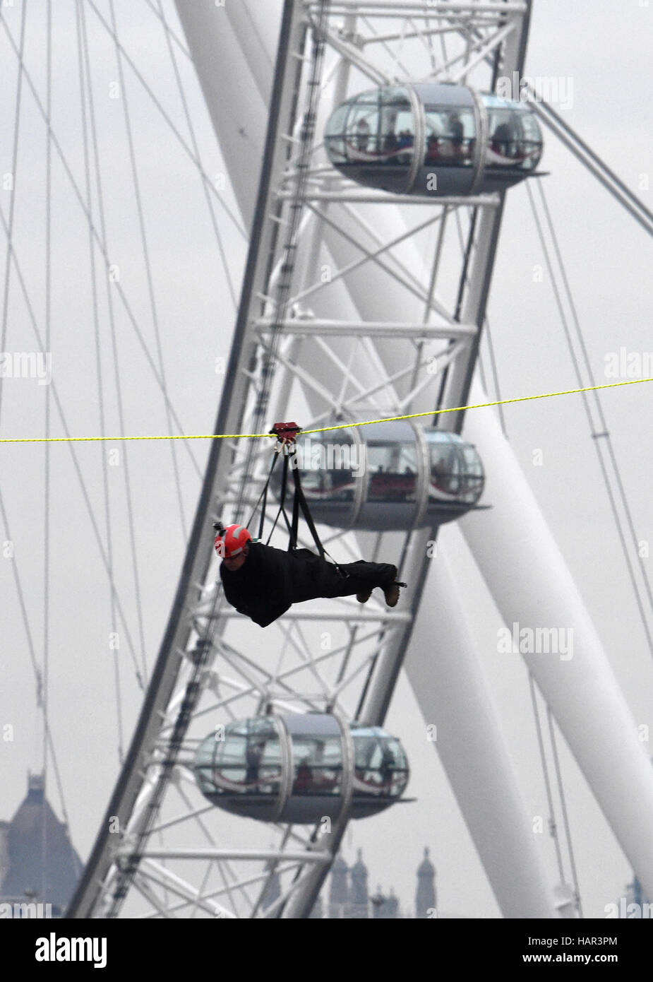 A fundraiser zip wires across the Thames from the roof of St Thomas' Hospital to the Houses of Parliament to launch a period of Christmas fundraising in aid of the Evelina London Children's Hospital. Stock Photo
