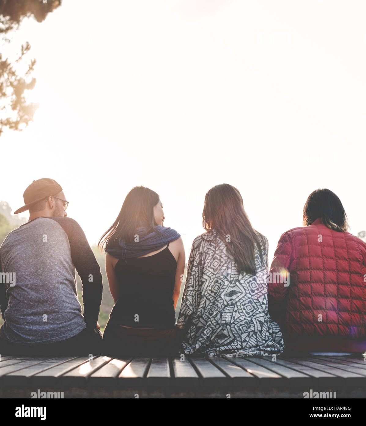 Friends Sitting in a Row Outdoors Concept Stock Photo - Alamy