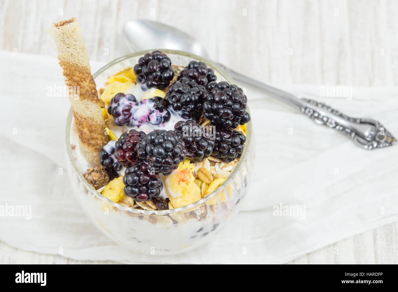 blackberry yogurt parfait in a glass cup on a white tablecloth closeup Stock Photo