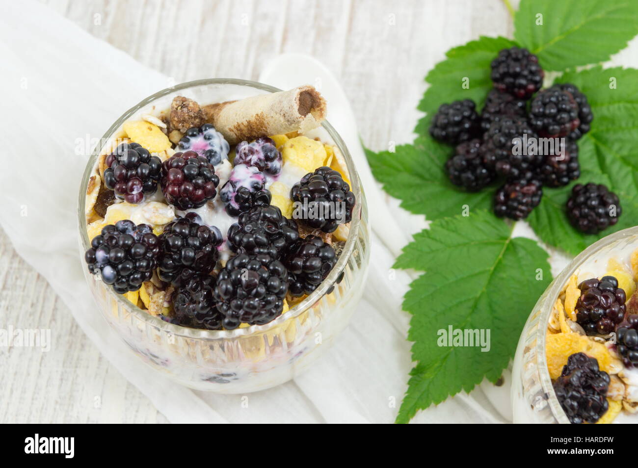 blackberry yogurt parfait in a glass cup on a white tablecloth closeup Stock Photo