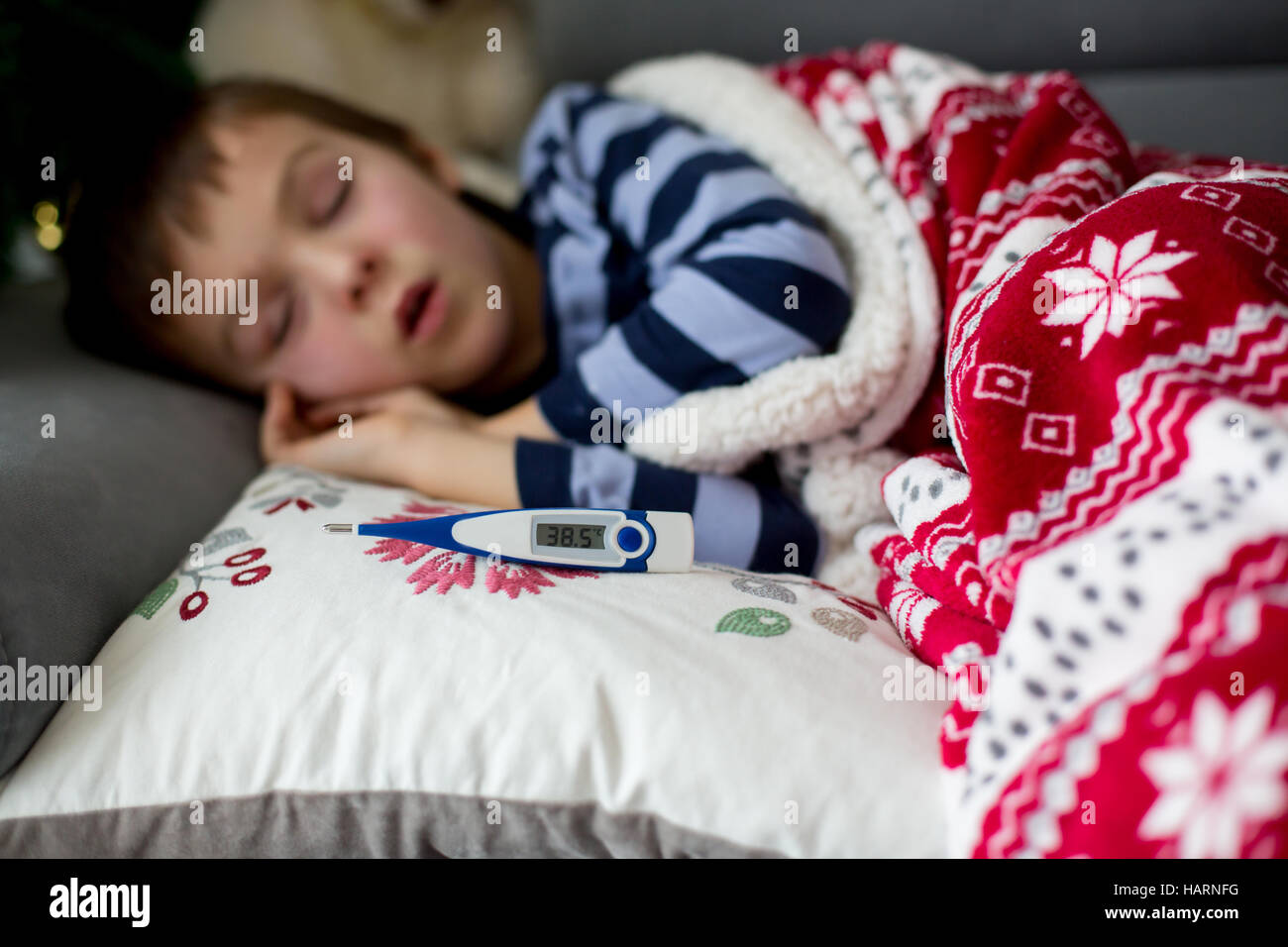 Sick little child, boy, with high fever sleeping on the couch at home