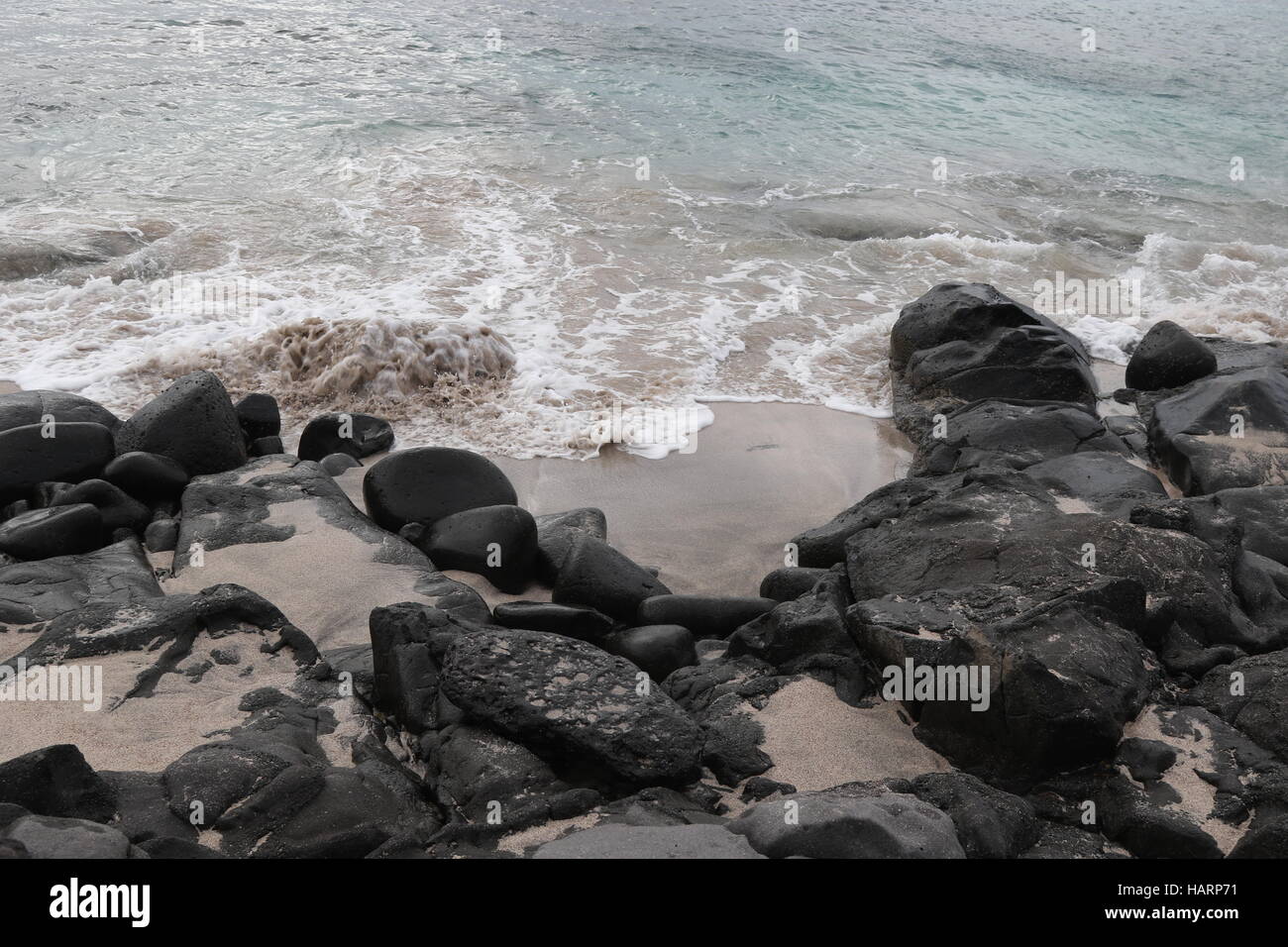 Waves rushing onto a sandy beach and hitting smooth rocks Stock Photo ...