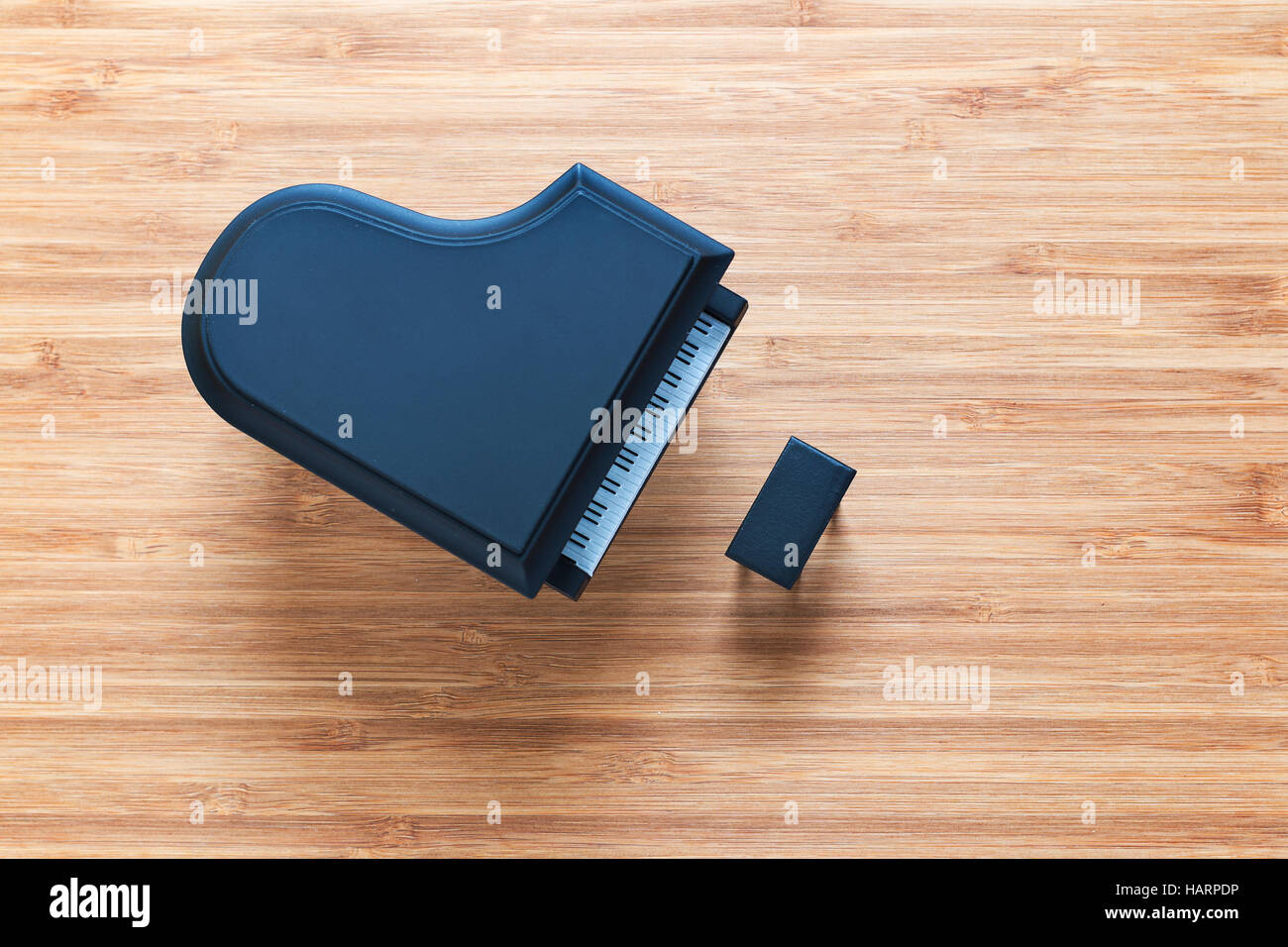 Black toy grand piano on a wooden floor with stool standing near it. Top view. Music concept. Stock Photo