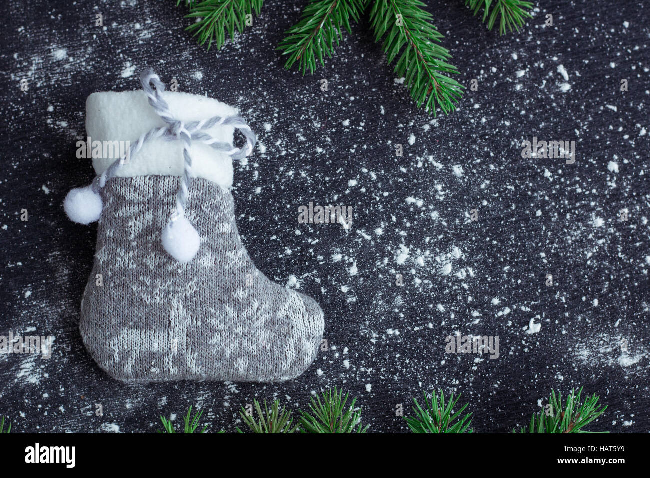 Christmas and New Year winter holiday snowbound composition of grey stocking on black space background with green fir tree branches Stock Photo