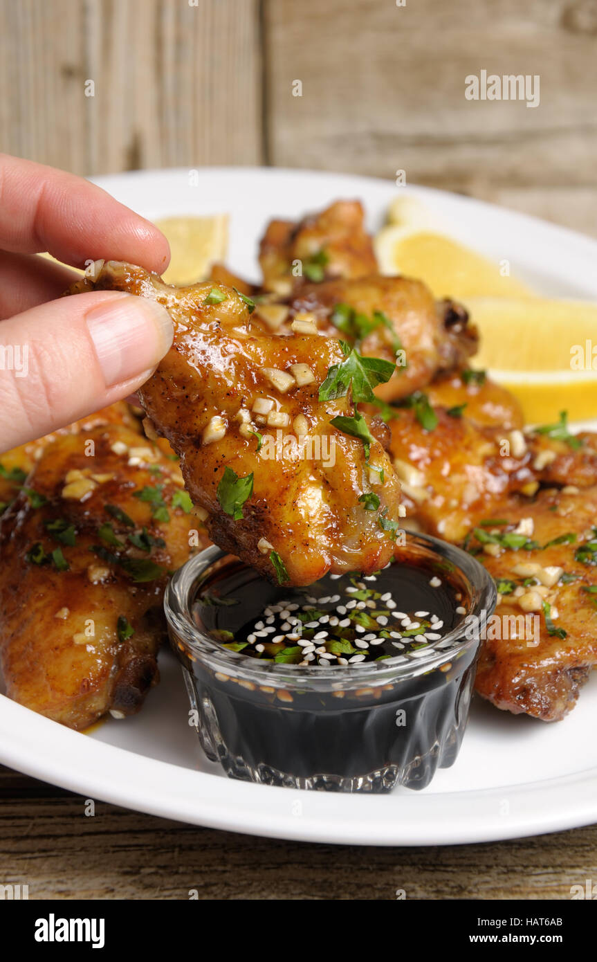 Fried chicken wing in ginger garlic marinade with herbs in hand over