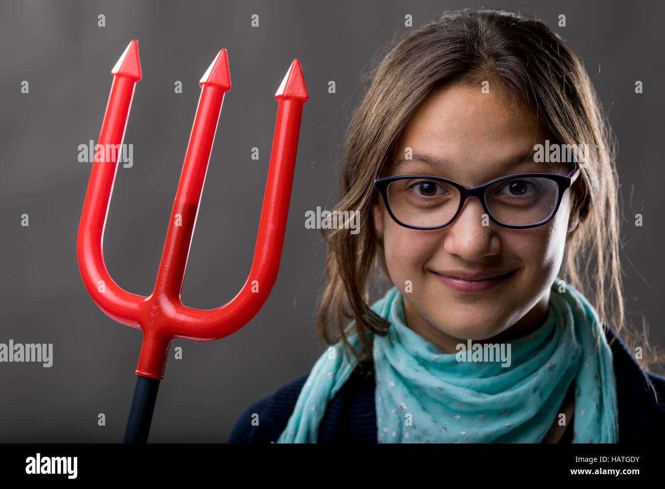 portrait of a little rascal girl with a red pitchfork meaning she is a little devil ready to