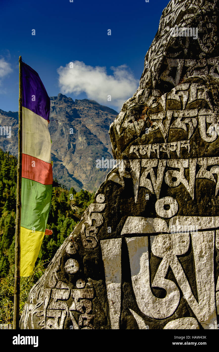 Colourful flag & Buddhist stone carvings to wish travellers luck en-route to Phakding, on Everest Base Camp trek Stock Photo