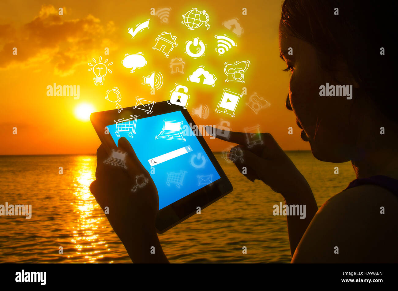Silhouette woman with digital tablet in hands at sunset beach Stock Photo