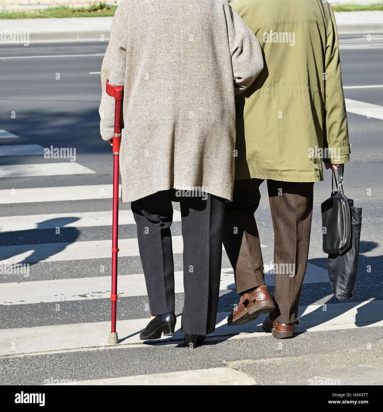 Old couple walks on the pedestrian crossing Stock Photo