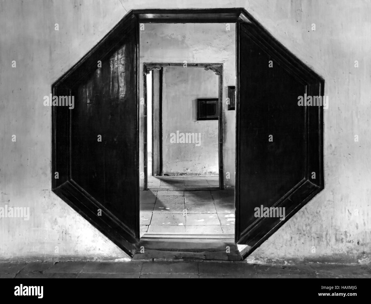 Octagonal open door to corridor with further doors in a plain wall of traditional chinese pavilion or palace. Stock Photo