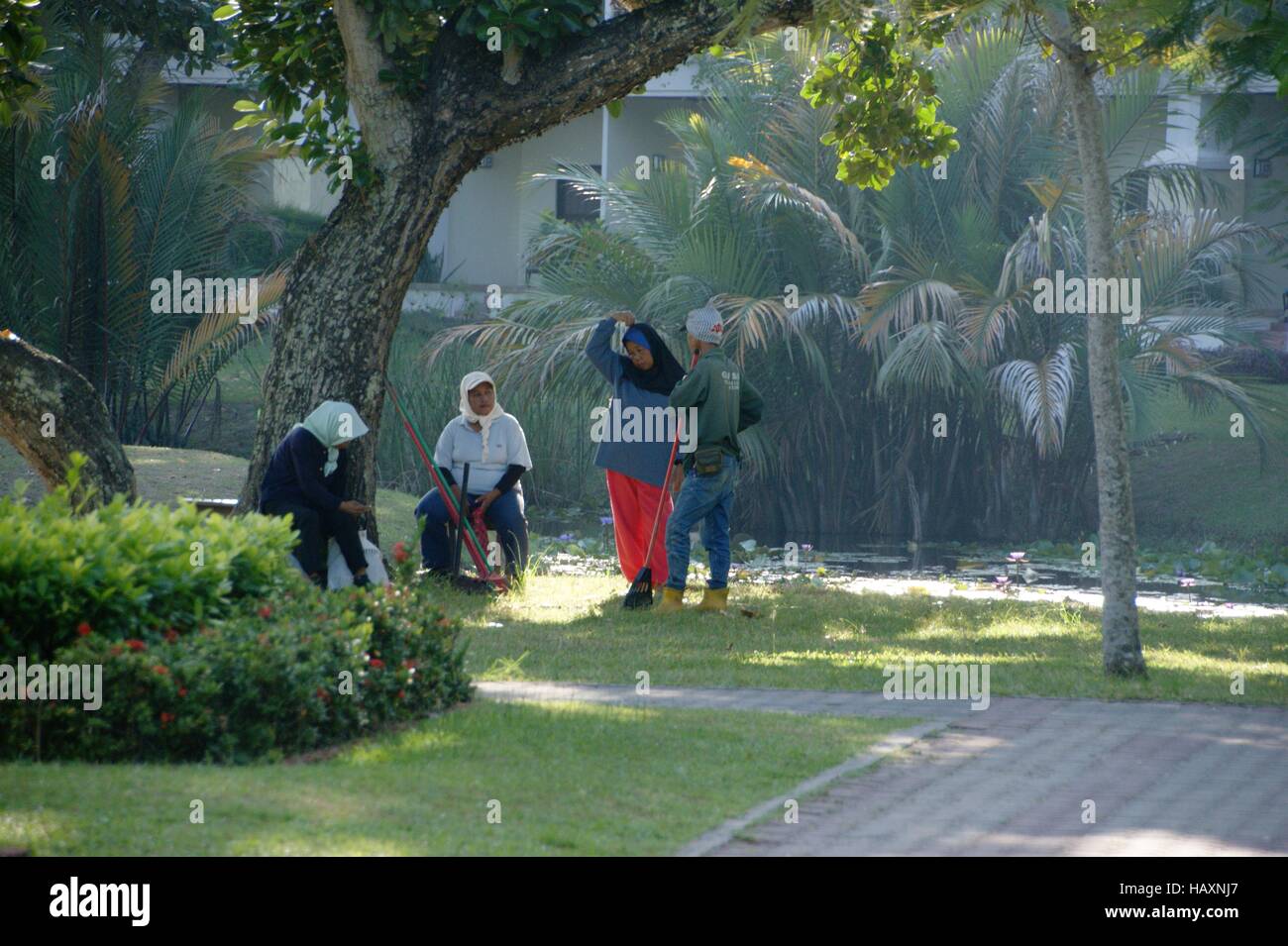 Malay Women clean hotel grounds. Nexus Resort & Spa Karambunai, Kota Kinabalu, Sabah, Borneo, Malaysia, Southeast Asia Stock Photo