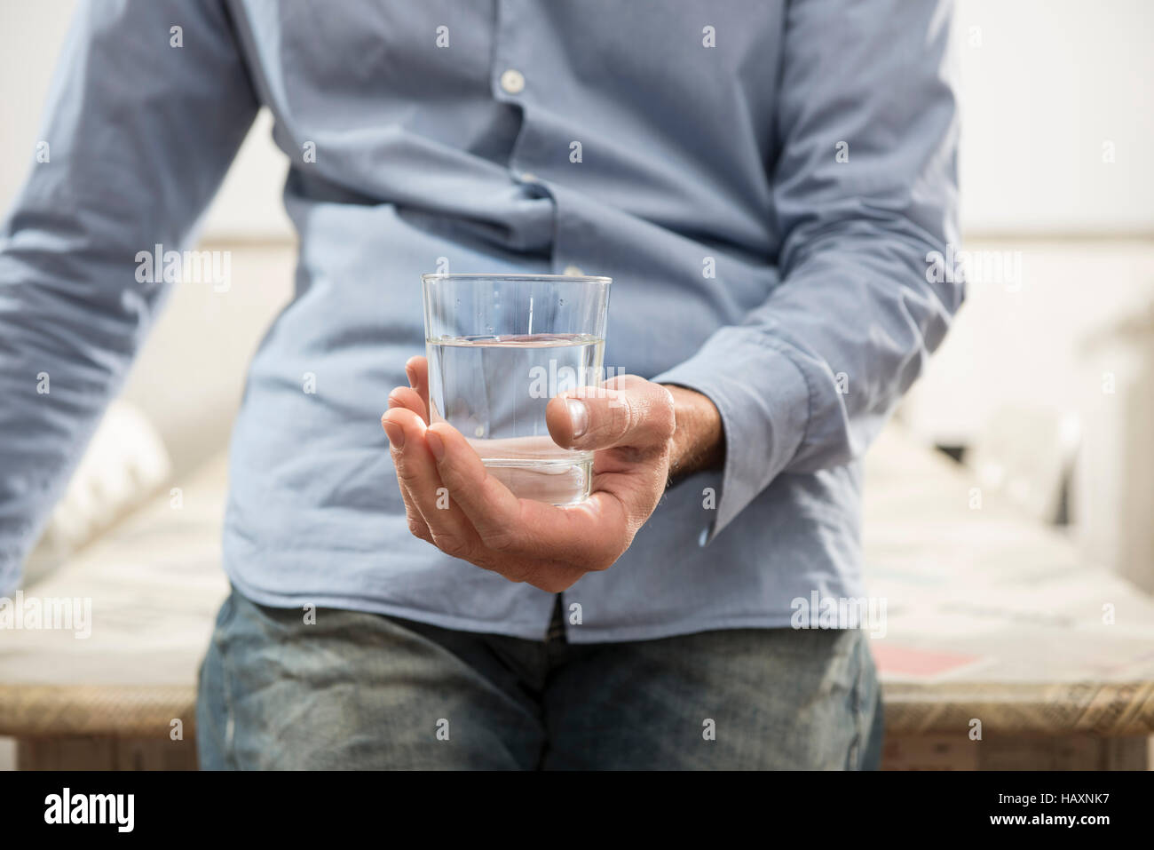 man who holds in hand a glass of water Stock Photo