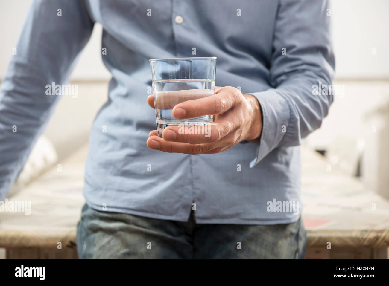 man who holds in hand a glass of water Stock Photo