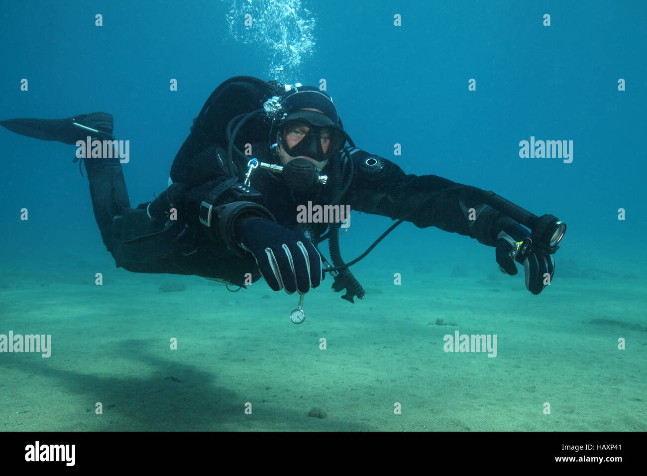 Professional scuba diver with black drysuit diving underwater in the
