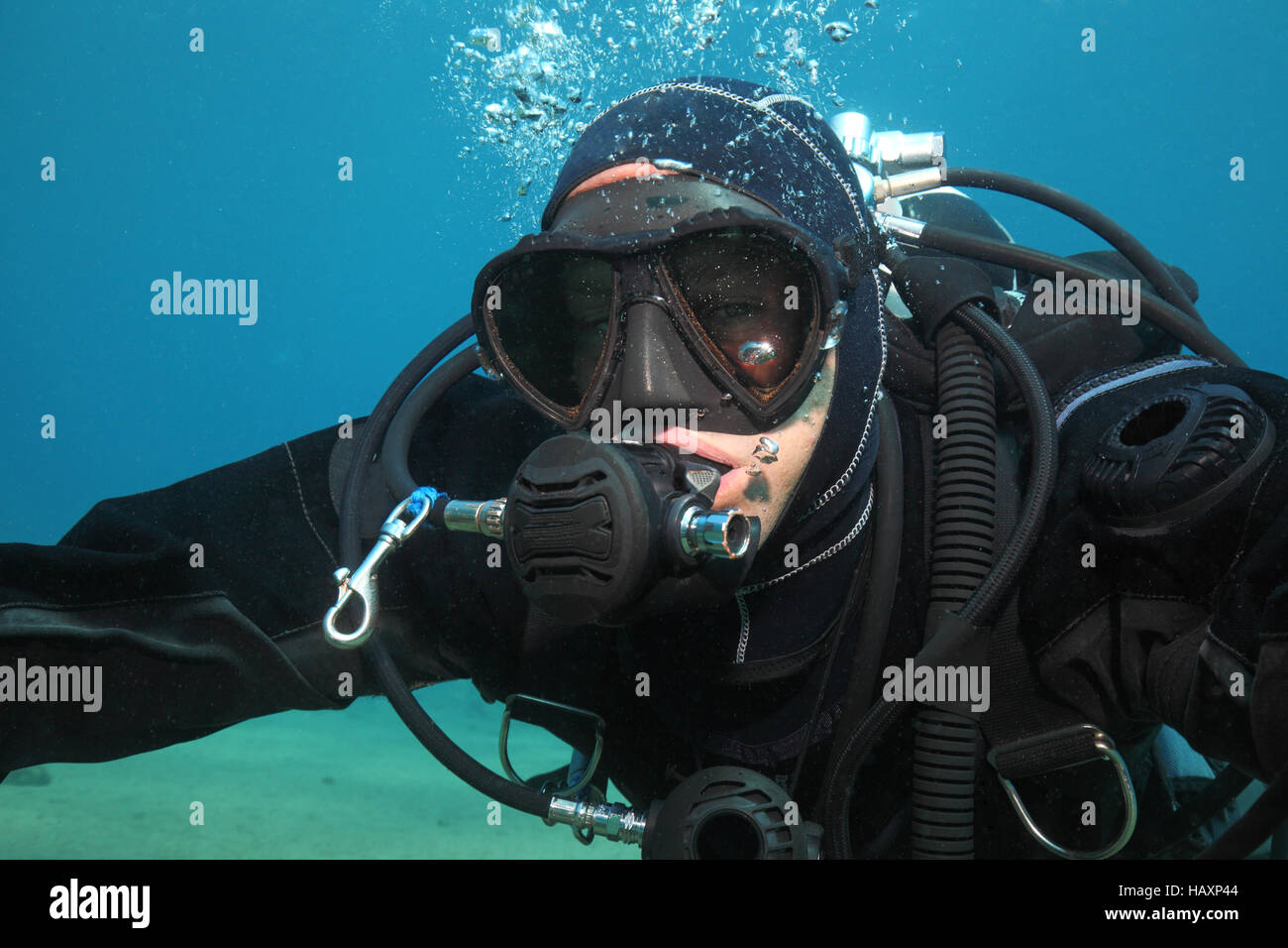 Professional scuba diver with black drysuit diving underwater in the
