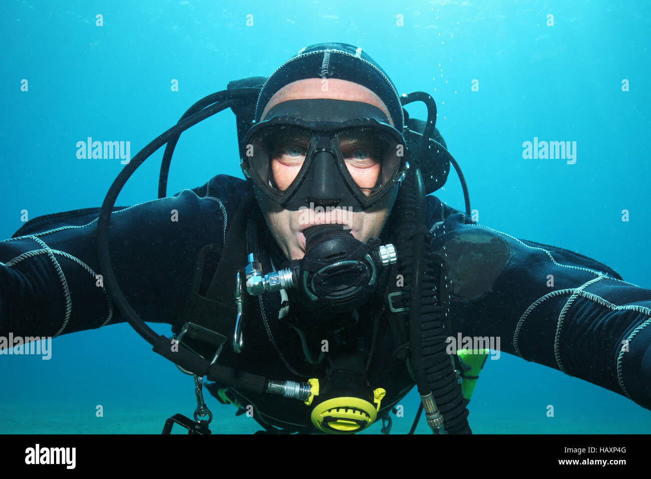 Professional scuba diver with black drysuit diving underwater in the