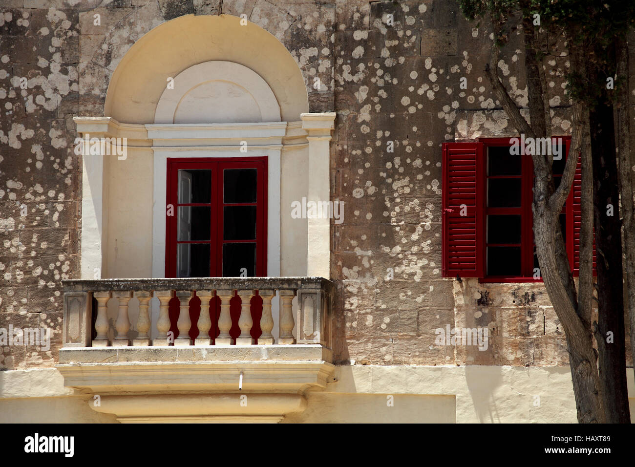 Landscape view of window with balcony and red shutters and tree Stock Photo