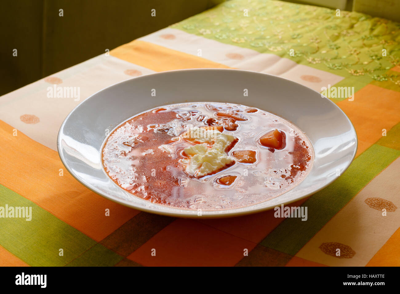 Simple traditional homemade red Ukrainian Borscht with smetana cream in a white porcelain plate Stock Photo