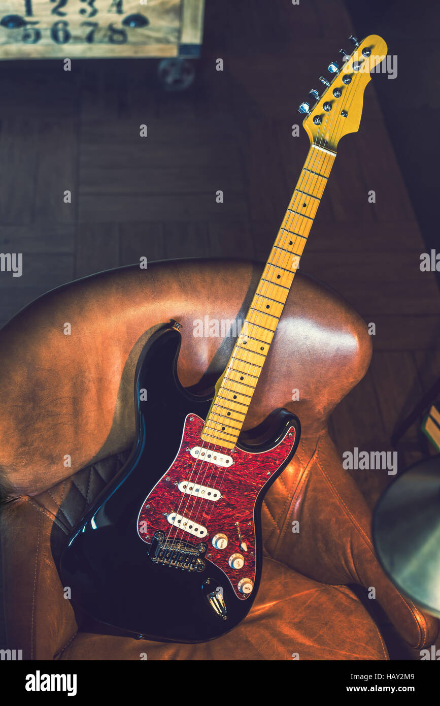 Electric Guitar Leaning Against a Couch. Electric Guitar. Black and Red