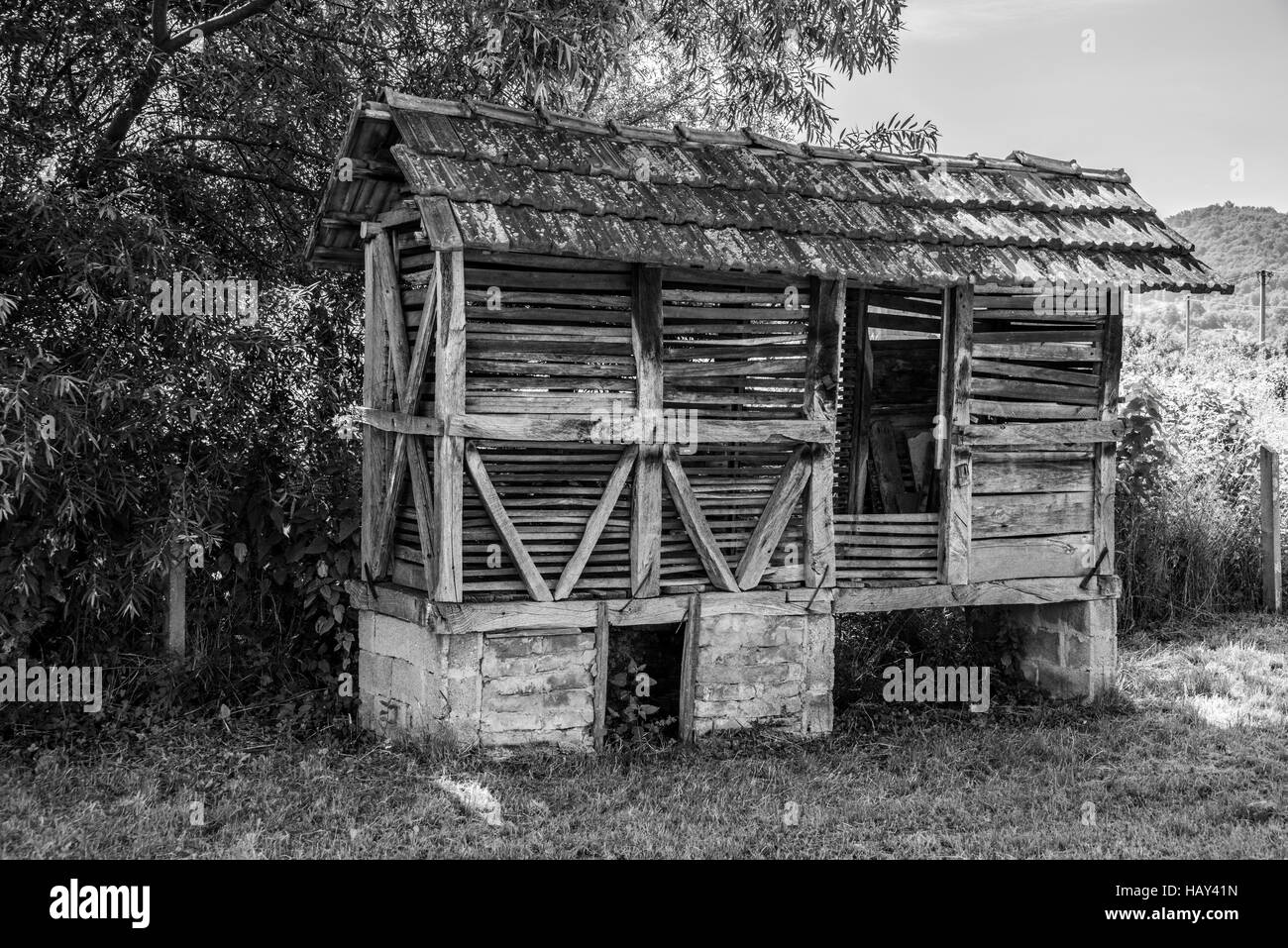 corn crib very old with concrete water foots on farmers land on sunny day in black and white color Stock Photo