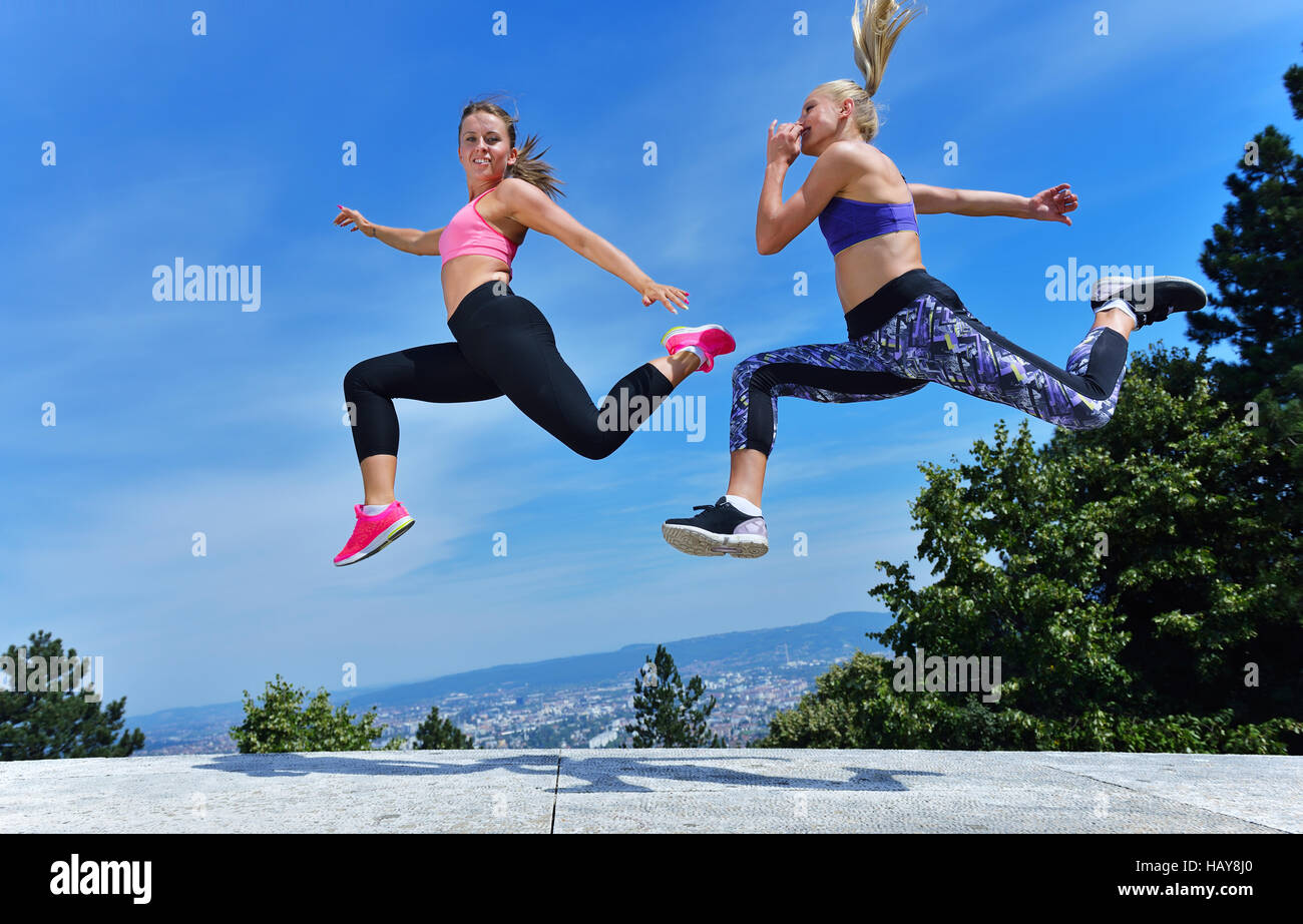Two happiness young women jumping over blue sky Stock Photo - Alamy