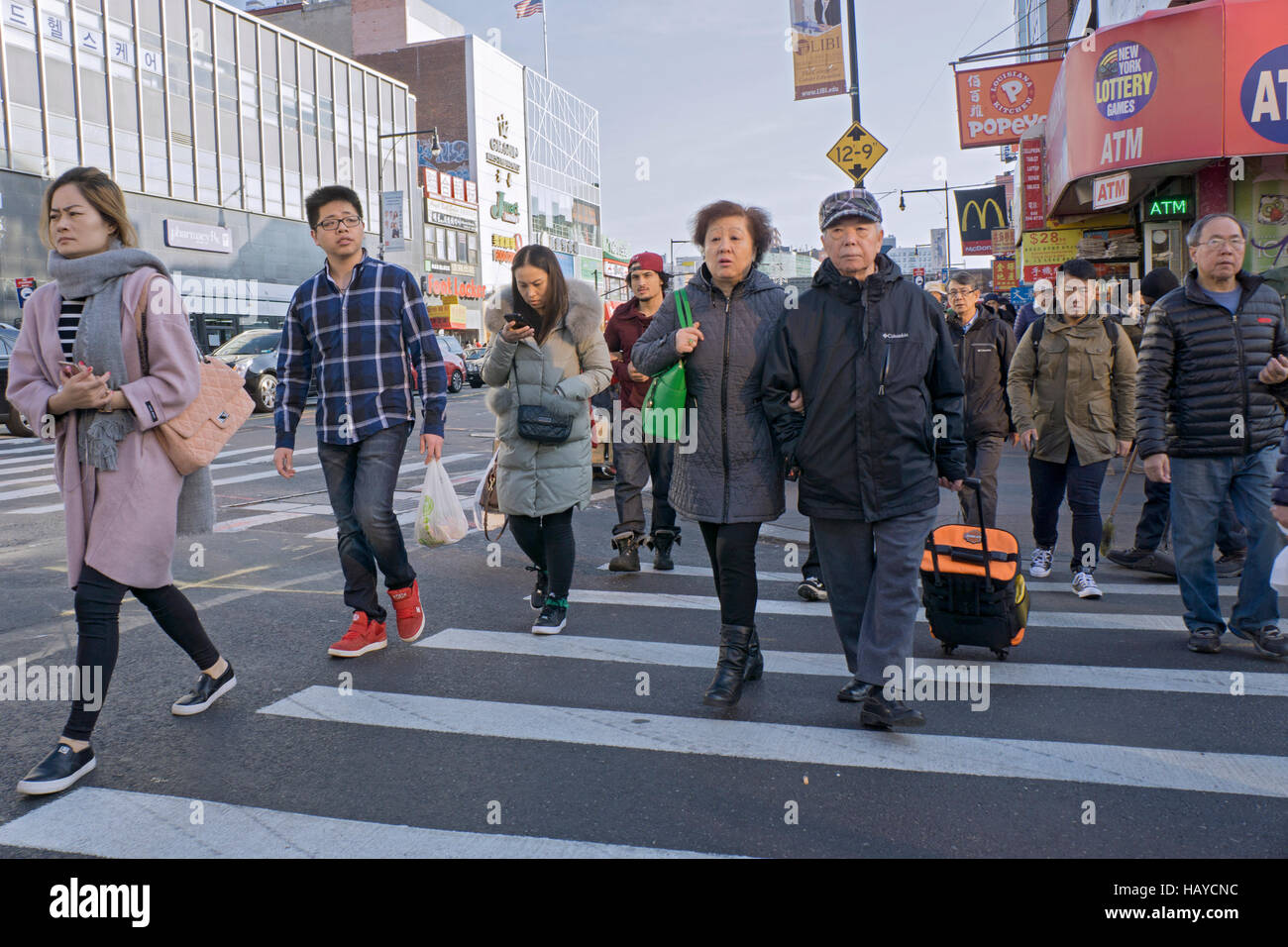 A group of people crossing Roosevelt Ave. on Main Street in Chinatown
