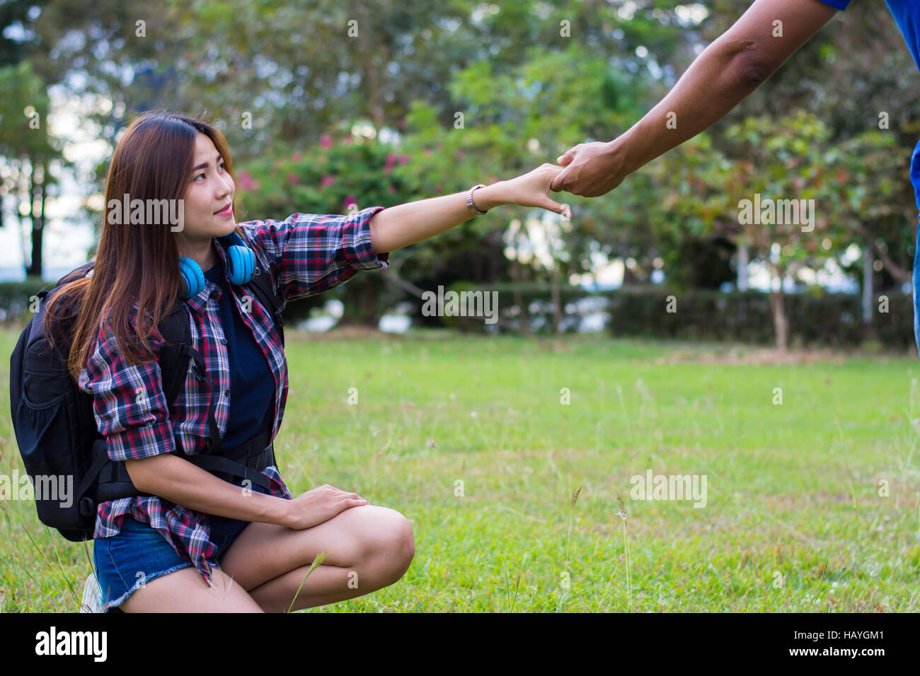 Woman sitting on the grass reaching to shake the hand of man. helping hand and love concept. Stock Photo