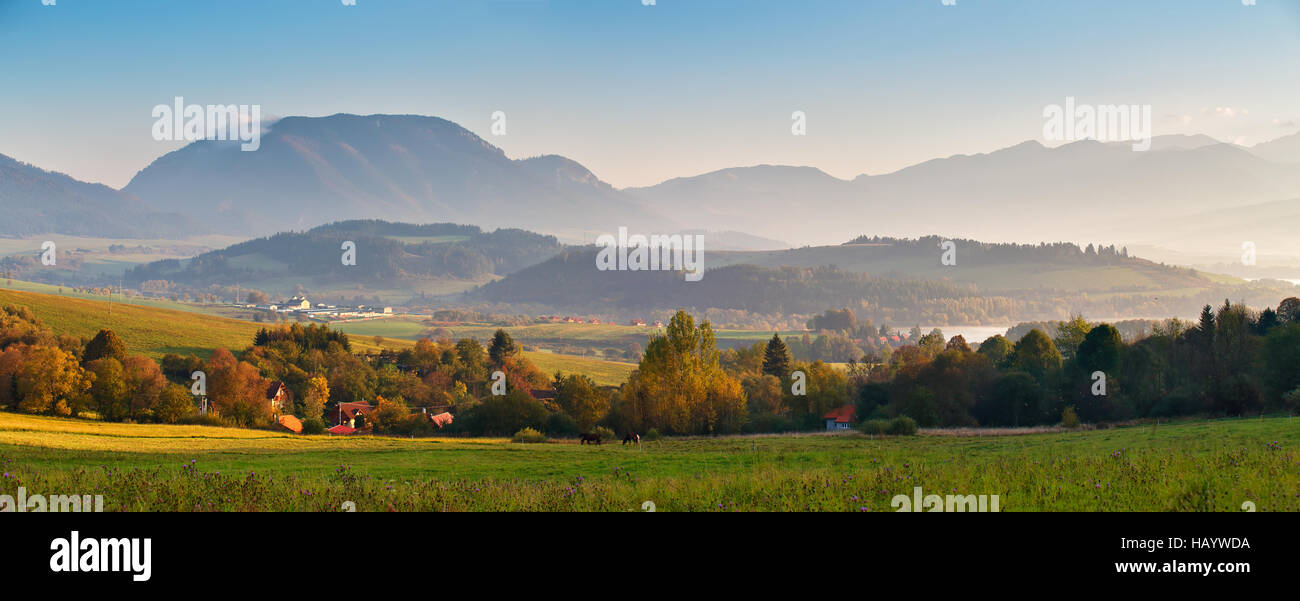 Slovakia autumn sunny morning panorama. Rural fall mountain scene. Village in valley. Stock Photo