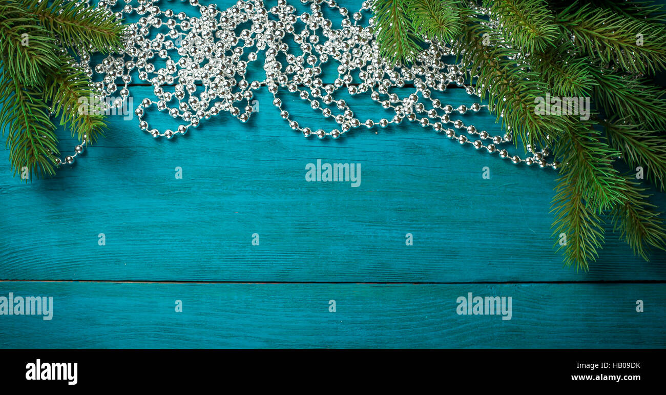 Christmas tree branch with silver beads on wooden table. Top view with ...