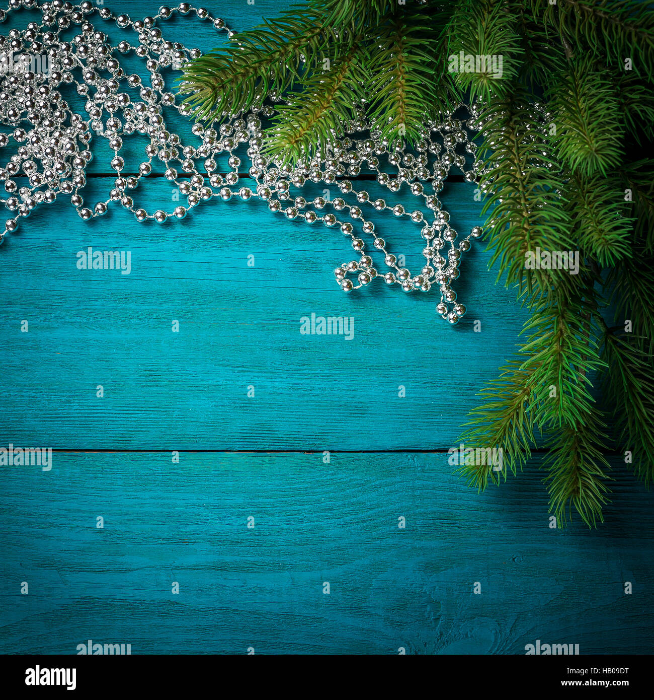 Christmas tree branch with silver beads on wooden table. Top view with ...